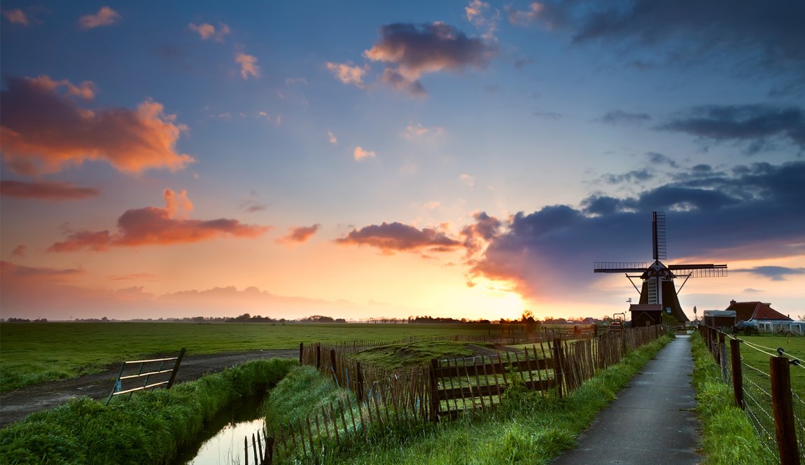 Colored Dutch sky with clouds behind windmill in typical Dutch landscape Colored Dutch sky with clouds behind windmill in typical Dutch landscape