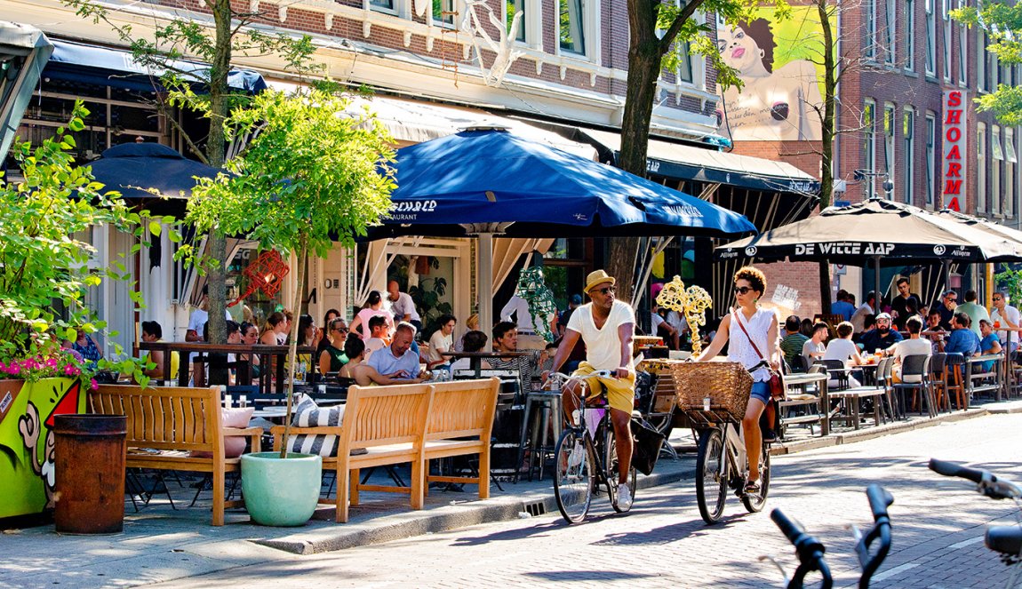 Couple cycling in summer through Witte de Withstraat Rotterdam Couple cycling in summer through Witte de Withstraat Rotterdam