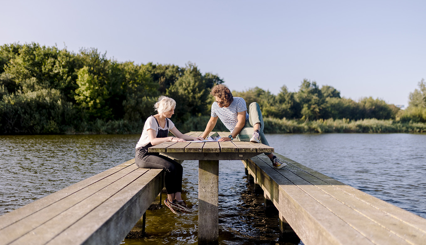 Man and woman sitting on wooden bench in the water Lauwersmeer Man and woman sitting on wooden bench in the water Lauwersmeer