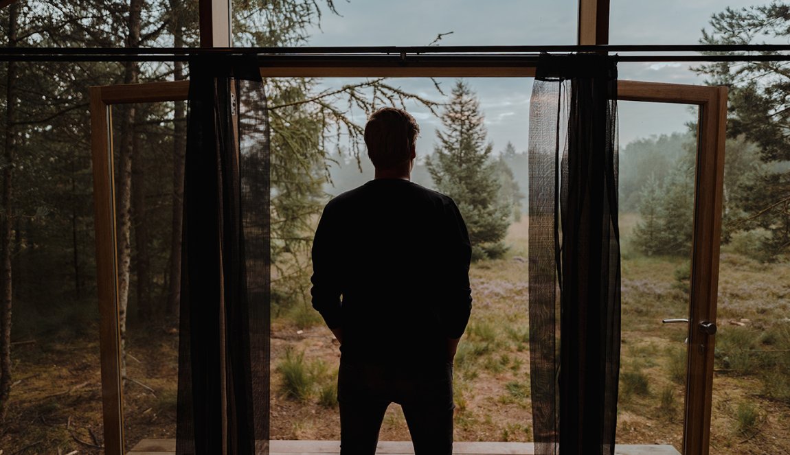 Man looks out of cottage Cabiner in Drenthe 