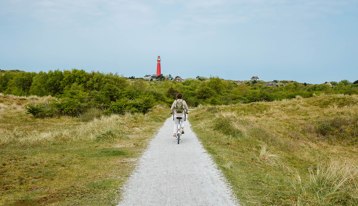 Cyclist on Schiermonnikoog with the lighthouse in view Cyclist on Schiermonnikoog with the lighthouse in view