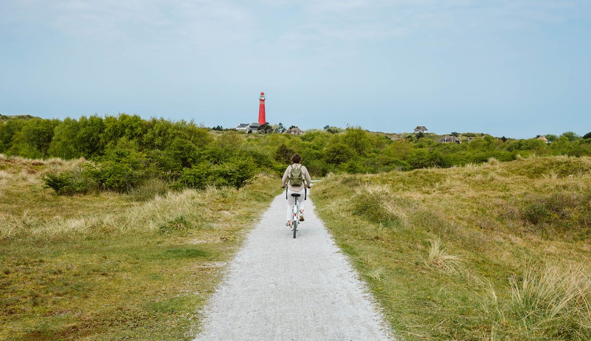 Cyclist on Schiermonnikoog with the lighthouse in view Cyclist on Schiermonnikoog with the lighthouse in view